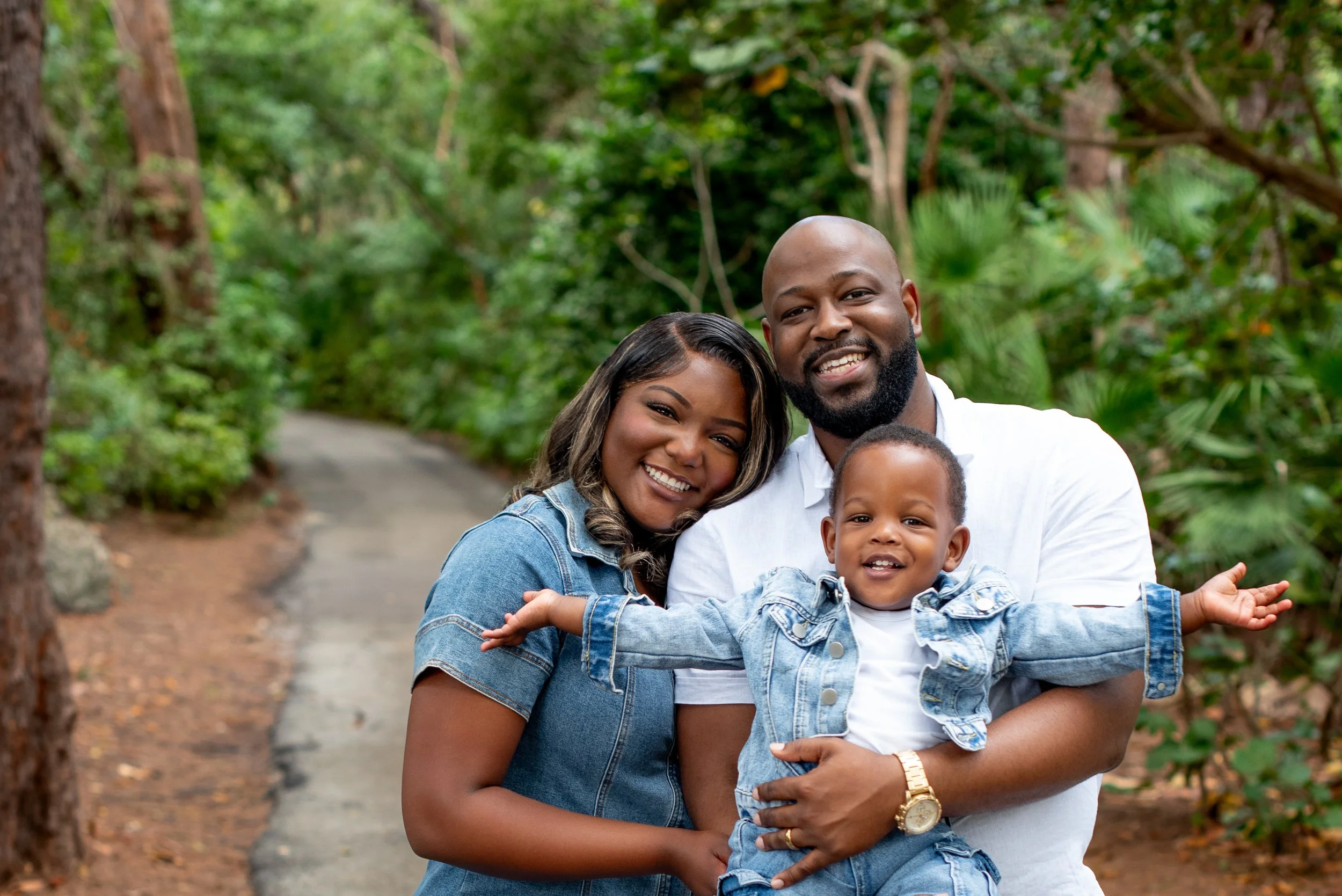 Husband, wife and chid in nature with warm smiles.