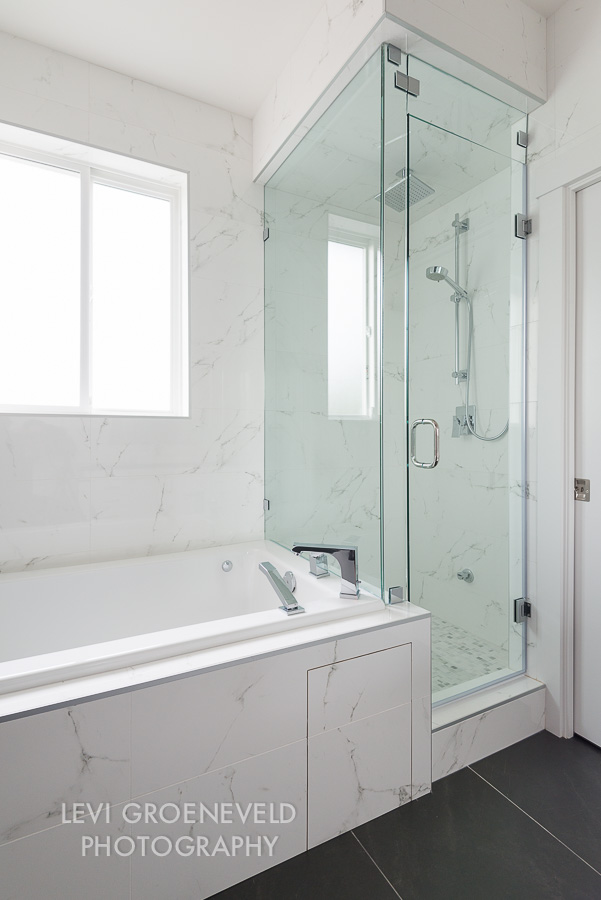 The other side of the master bathroom features a jacuzzi tub and steam shower for the ultimate relaxation. The wall tile is a beautiful faux white marble and covers three of the walls completely. 