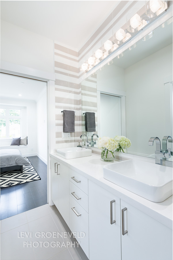 The shared bathroom joins the other two bedrooms with pocket doors on either side. We created a custom striped tile pattern on the walls around the double sinks to add interest and texture to the space. 
