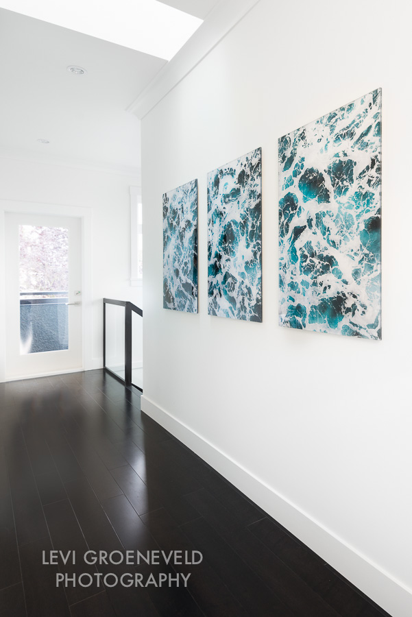 A white gallery wall in the hallway lends itself to perfectly host three beautiful pieces of art by Levi Groeneveld . The pieces add a welcome pop of colour to the space. 