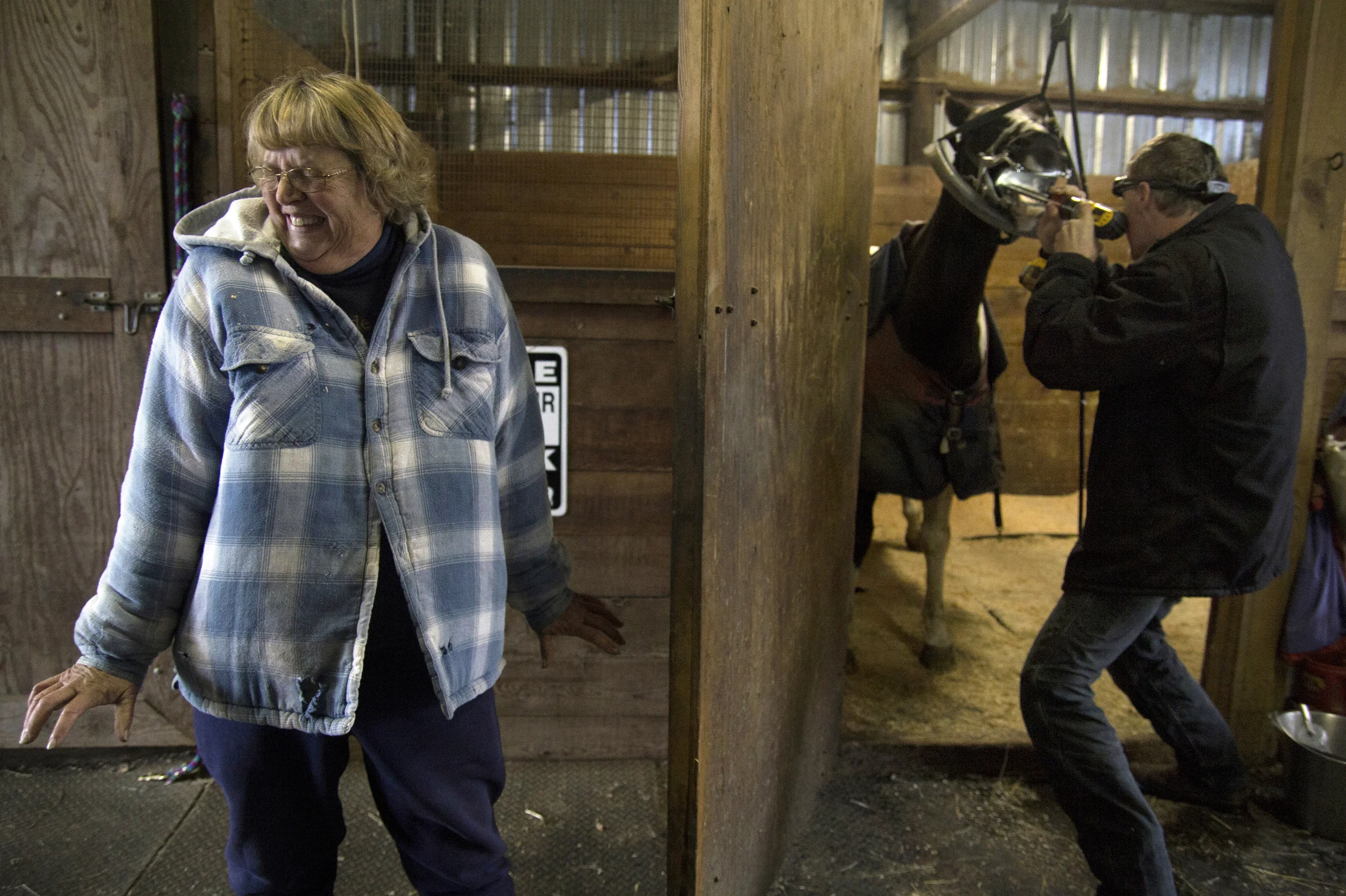   21 Nov. 2012, Eugene, OR --&nbsp; Eve Burleson, left, cringes at the sound of a file as veterinarian Dr. Jeff Pelton performs dentistry work on her horse at her property in Eugene. Burleson is interested in the float process but detests the sound o