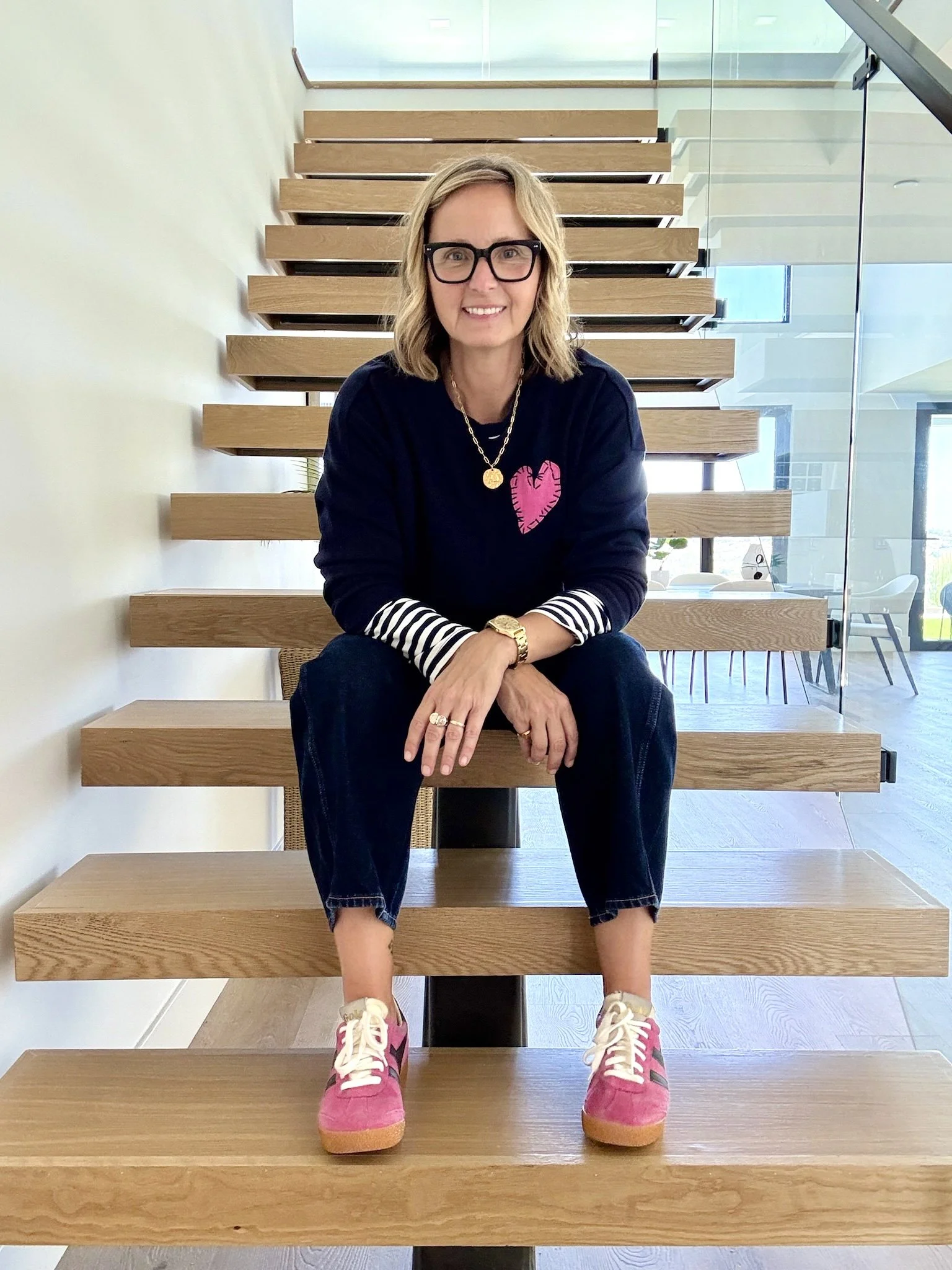 Karrie Franks Soth OC Realtor, sitting on a floating stairs case in a modern home located in Laguna Niguel