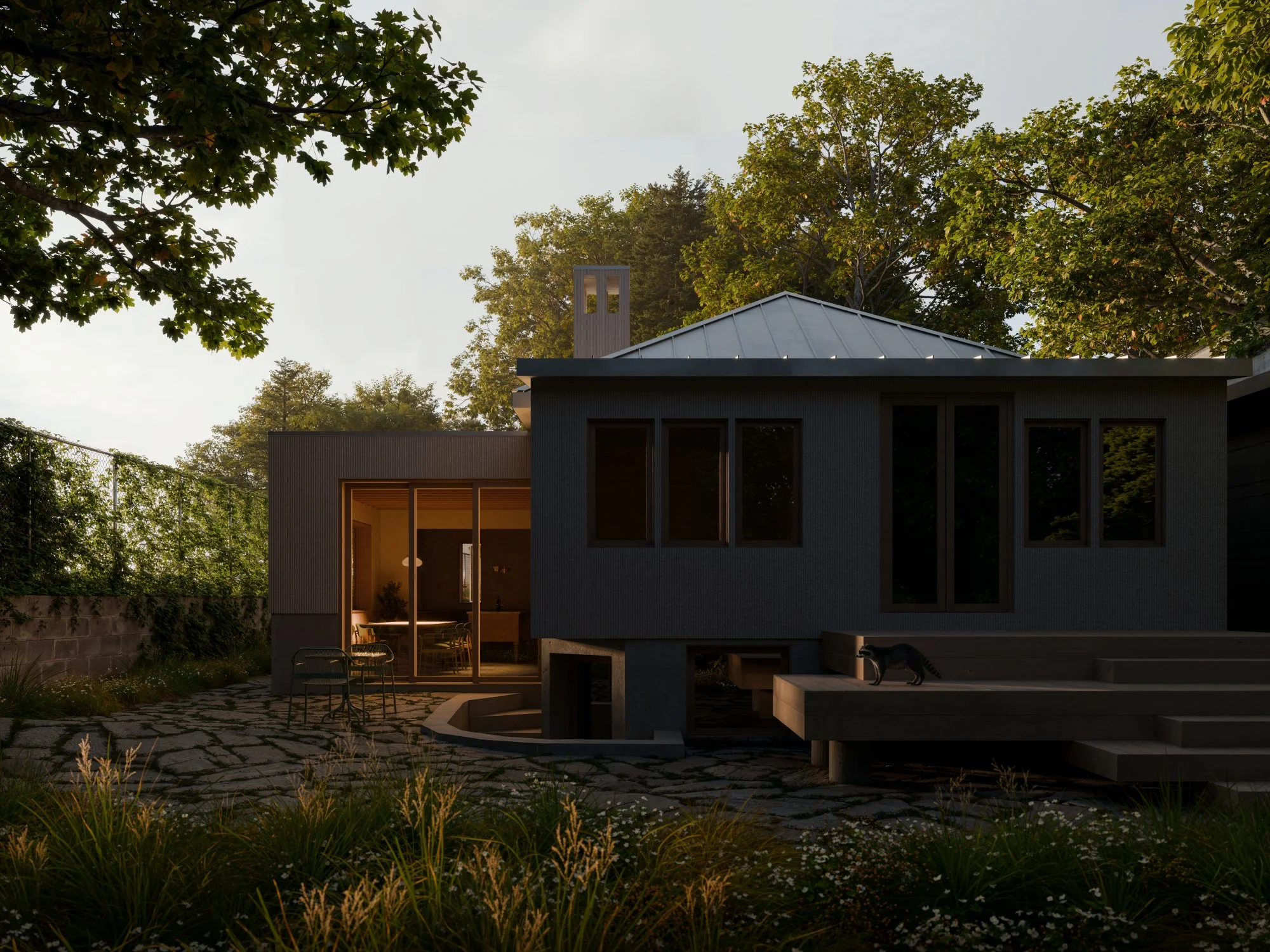 Modern house with large windows and a sloped metal roof surrounded by trees and a stone pathway in the backyard, illuminated by evening light.