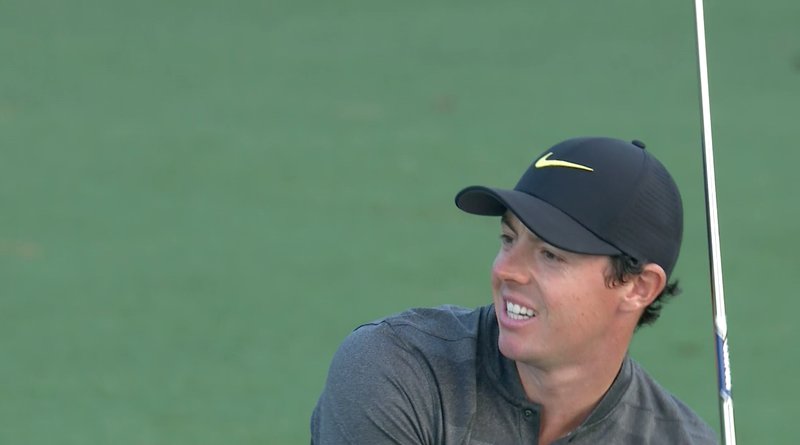 Rory McIlroy leans left after leaking his approach into a bunker at the 18th. It plugged and he finished with a bogey