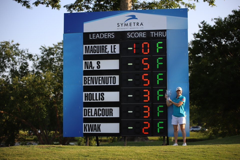 Leona Maguire with trophy at leaderboard (distance).JPG