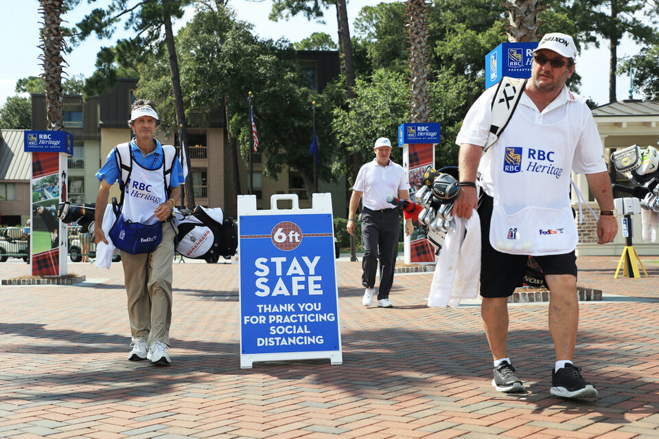  HILTON HEAD ISLAND, SOUTH CAROLINA - JUNE 19: Caddies walk past signage promoting social distancing as a COVID-19 precaution during the second round of the RBC Heritage on June 19, 2020 at Harbour Town Golf Links in Hilton Head Island, South Carolin