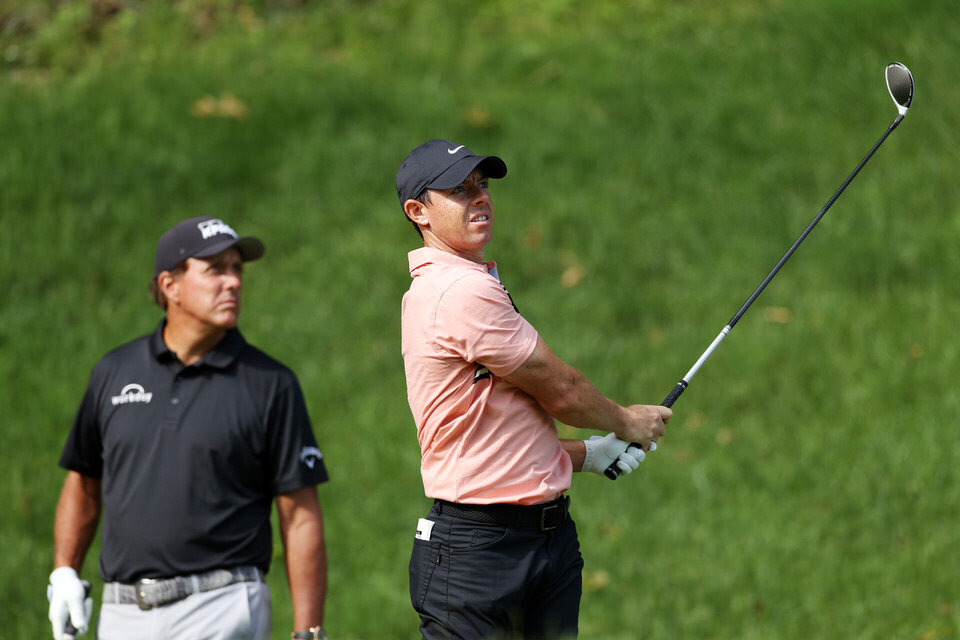 CROMWELL, CONNECTICUT - JUNE 25: Rory McIlroy of Northern Ireland plays his shot from the 15th tee as Phil Mickelson of the United States looks on during the first round of the Travelers Championship at TPC River Highlands on June 25, 2020 in Cromwe
