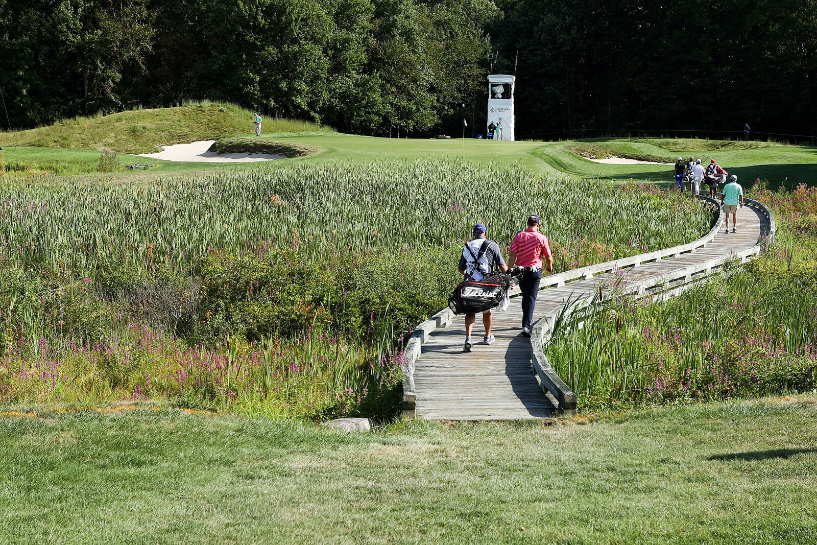  NORTON, MASSACHUSETTS - AUGUST 21: Robby Shelton of the United States, Troy Merritt of the United States and Si Woo Kim of South Korea cross the bridge to the eighth green with their caddies during the second round of The Northern Trust at TPC Bosto