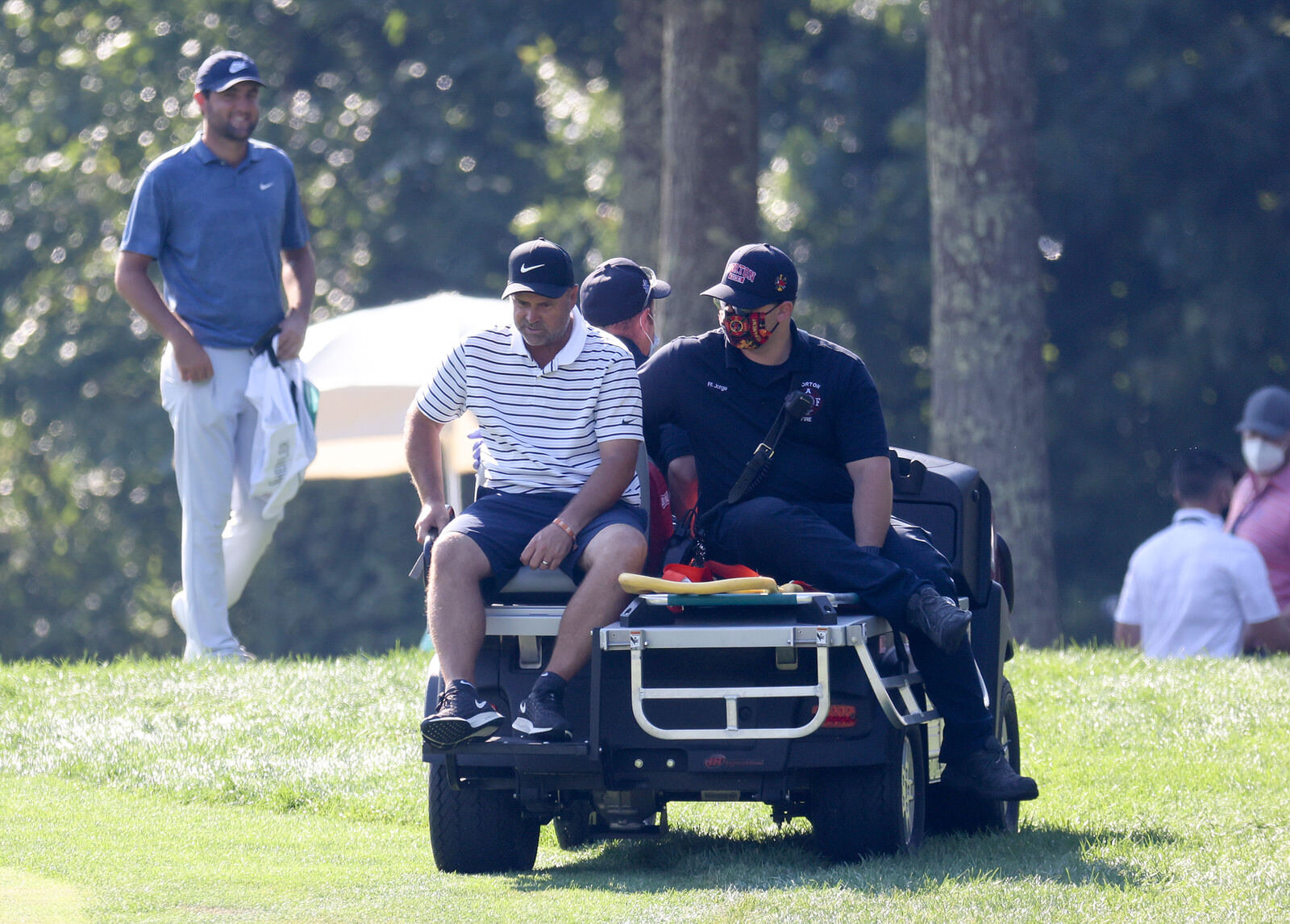  NORTON, MASSACHUSETTS - AUGUST 23: Caddie Scotty Macguiness leaves the course on a golf cart due to an injury as Scottie Scheffler of the United States looks on during the final round of The Northern Trust at TPC Boston on August 23, 2020 in Norton,