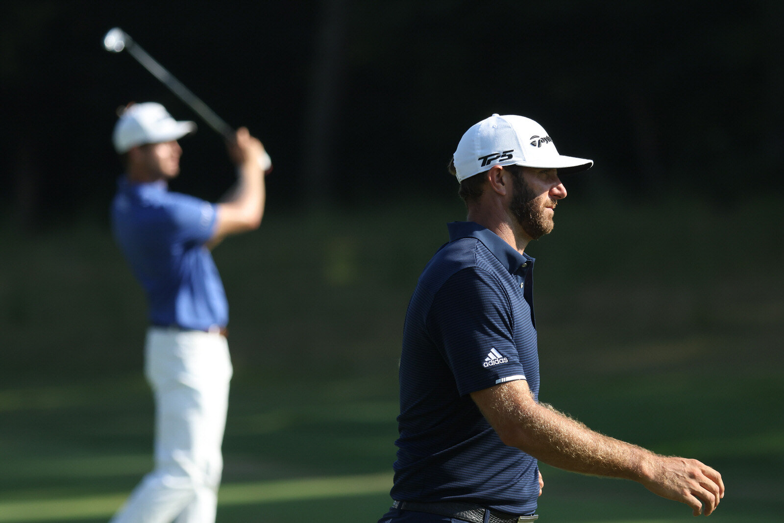  NORTON, MASSACHUSETTS - AUGUST 23: Dustin Johnson of the United States walks by as Harris English of the United States hits his second shot on the ninth hole during the final round of The Northern Trust at TPC Boston on August 23, 2020 in Norton, Ma