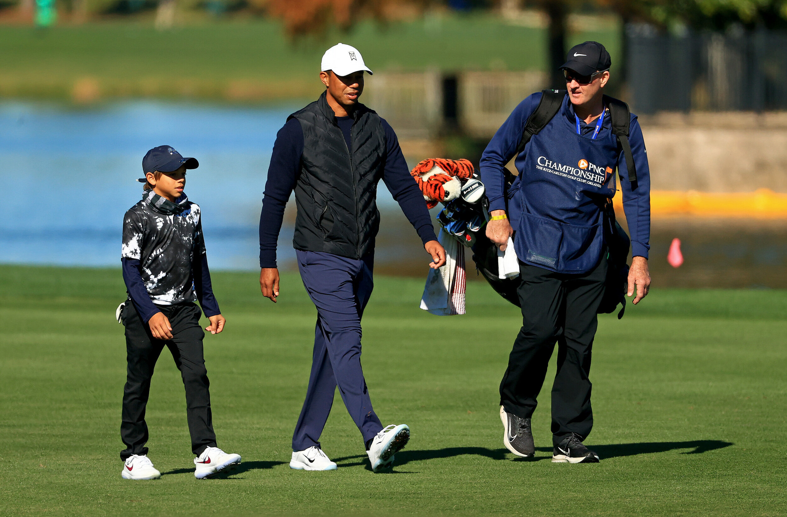  ORLANDO, FLORIDA - DECEMBER 18: Tiger Woods of the United States, son Charlie Woods, and caddie Joe LaCava  walk up the 18th hole during the Pro-Am for the PNC Championship at the Ritz Carlton Golf Club on December 18, 2020 in Orlando, Florida. (Pho