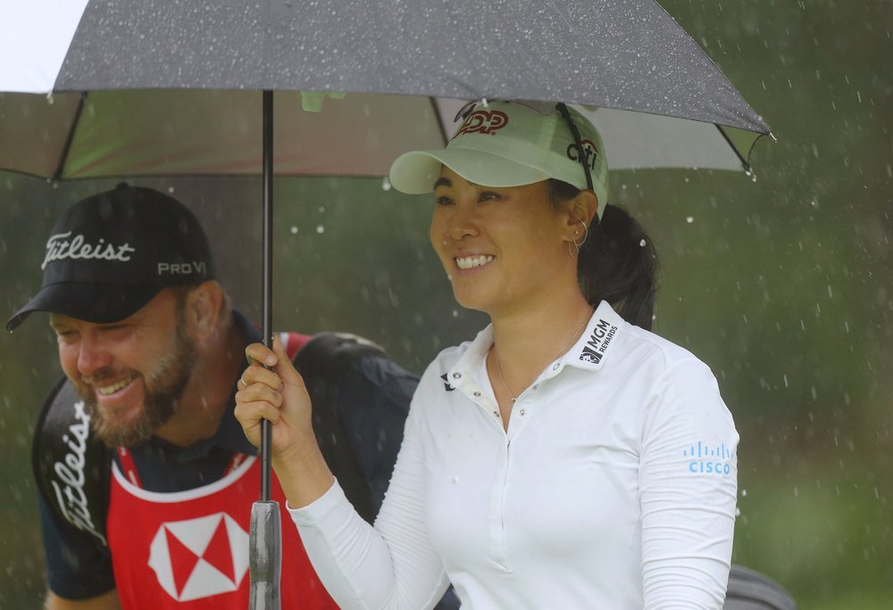 Danielle Kang of The United States and her caddie shelter from the rain under an umbrella during Day Two of the HSBC Women's World Championship at Sentosa Golf Club on March 03, 2023 in Singapore. (Photo by Andrew Redington/Getty Images)