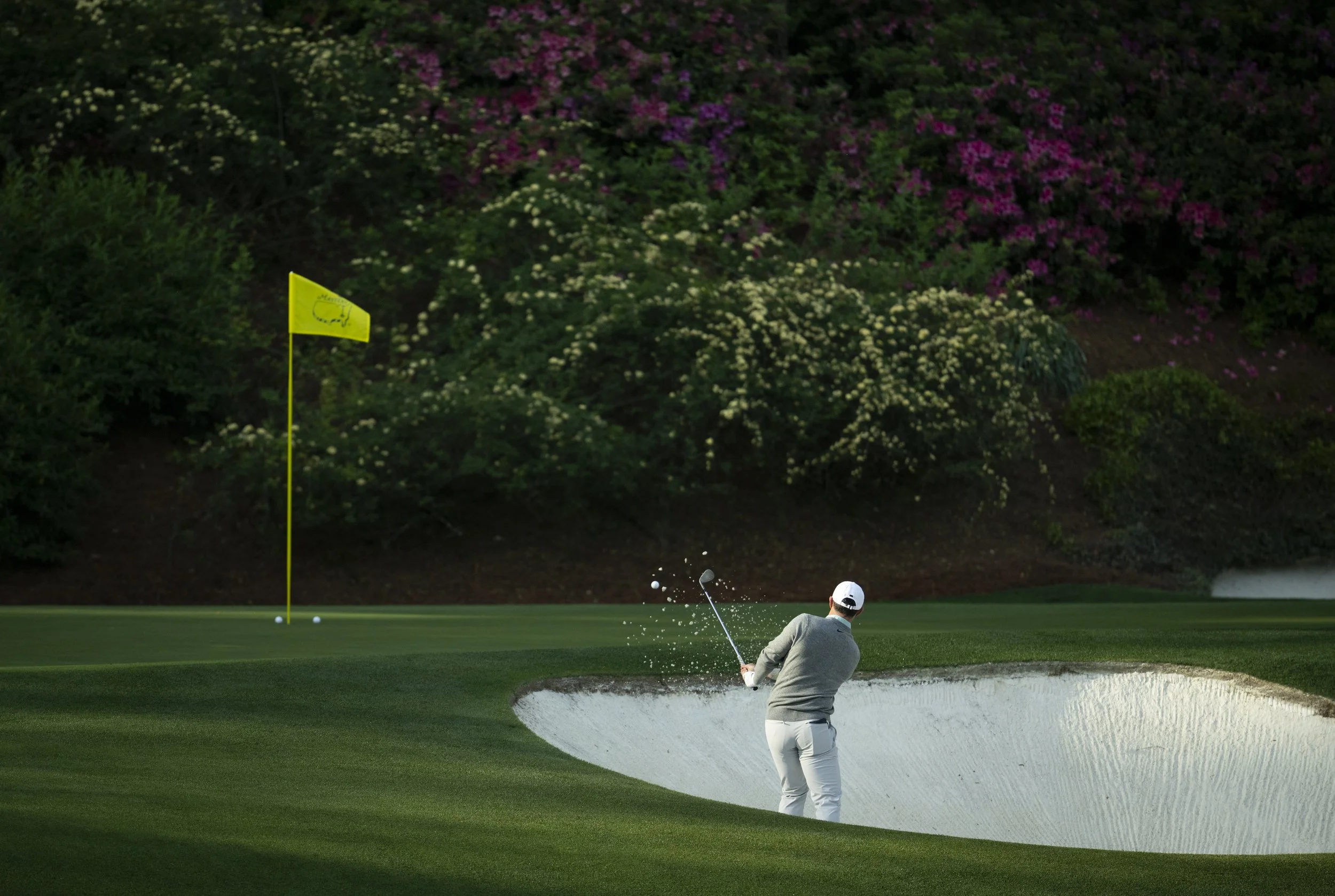 Masters champion Rory McIlroy of Northern Ireland plays a stroke from a bunker on the No. 12 hole during a practice round prior to the Masters at Augusta National Golf Club, Wednesday, April 08, 2026.