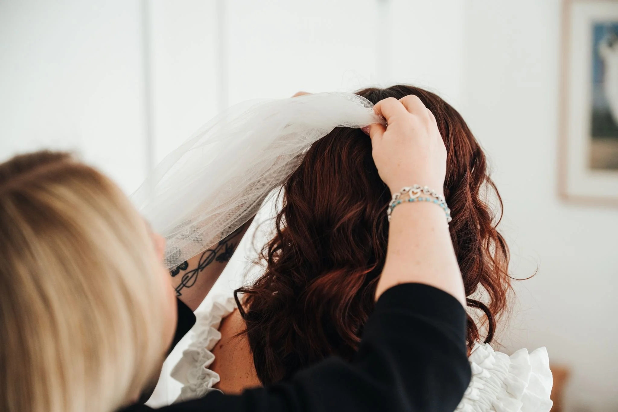Person placing a veil on a bride with red hair during a wedding ceremony.
