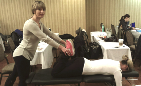 Here I am assessing my colleague’s pelvic rotation by feeling the stiffness in the legs as you raise them towards the buttocks. The stiffer leg indicates the side that would need correction. The adjustment is very safe, gentle, and comfortable especially because you are lying face down with pregnancy pillows that contour your belly! It may even be the first time you get to lie on your belly in your 2nd or 3rd trimester!