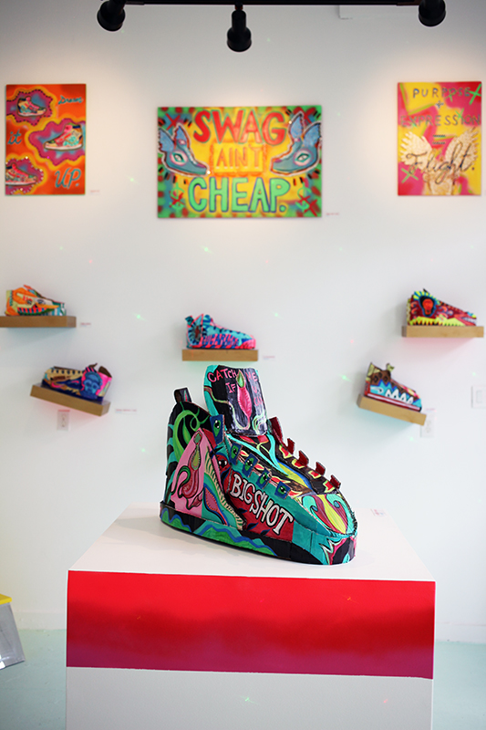 Hand painted cardboard kicks displayed on custom shelves with colorful EL lights.