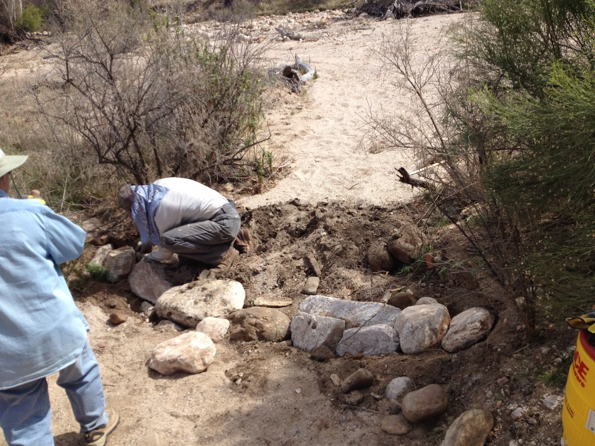 Work begins on the first one rock dam at the mouth of the arroyo.