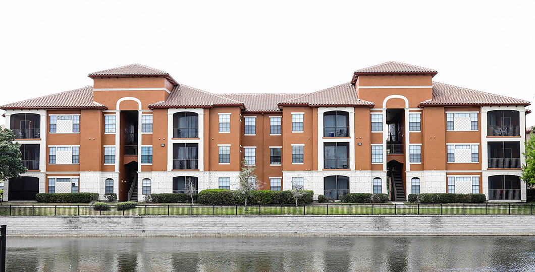 tan apartment building with pond in front