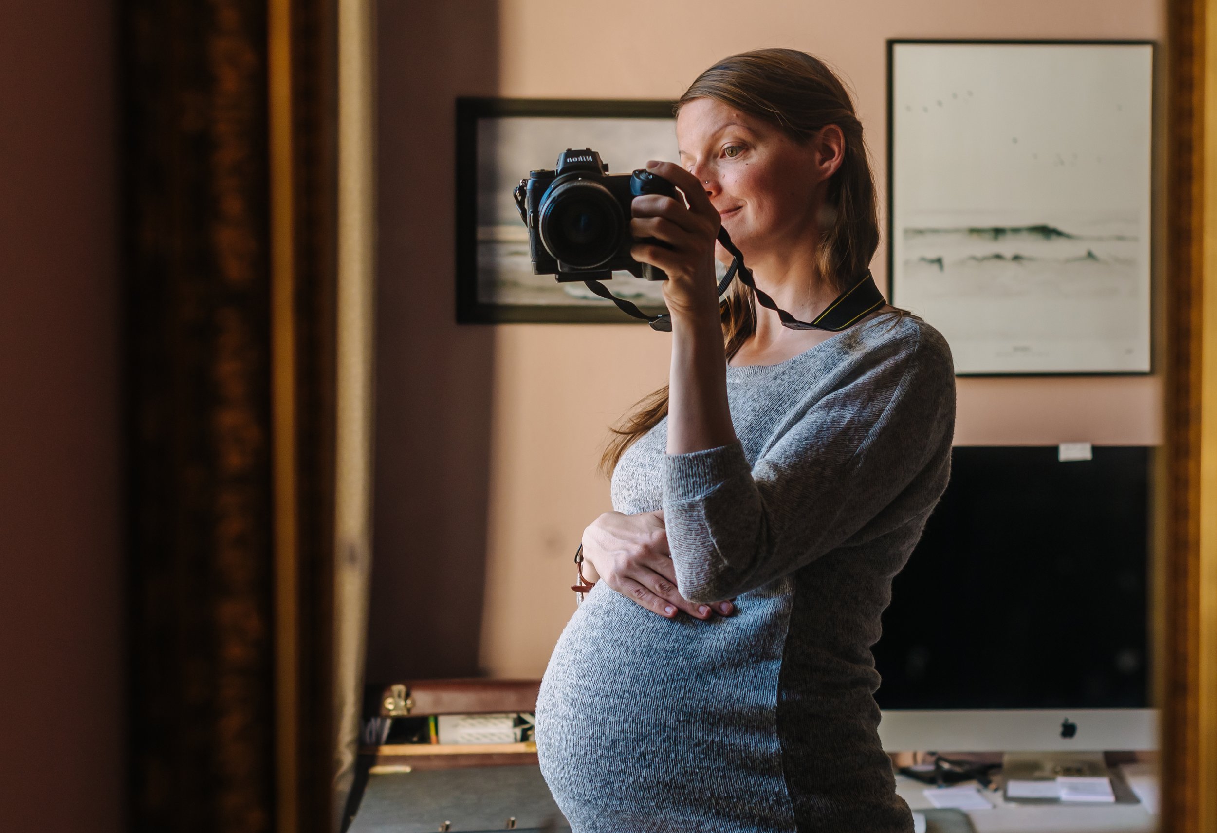 Schwangere Frau fotografiert ihren Babybauch mit einem Spiegel Selfie zu Hause.