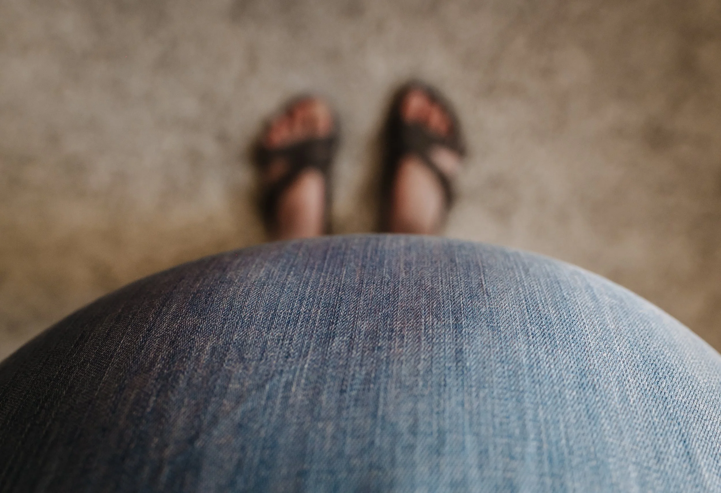 Schwangere Frau fotografiert ihren Babybauch von oben mit beiden Händen auf dem Bauch als kreative Babybauch Foto Idee.