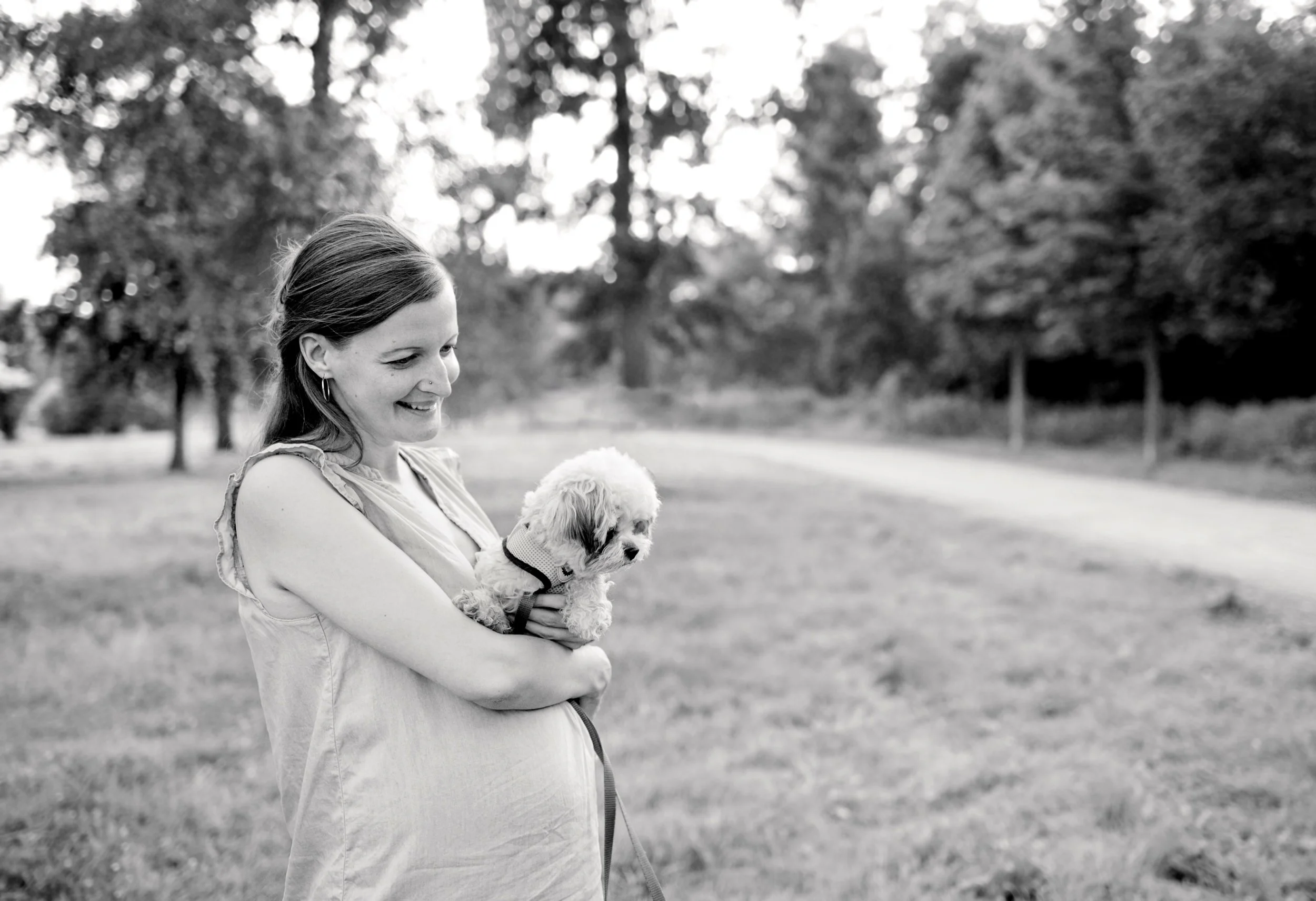 Schwangere Frau mit Hund bei einem Babybauch Shooting im Freien.