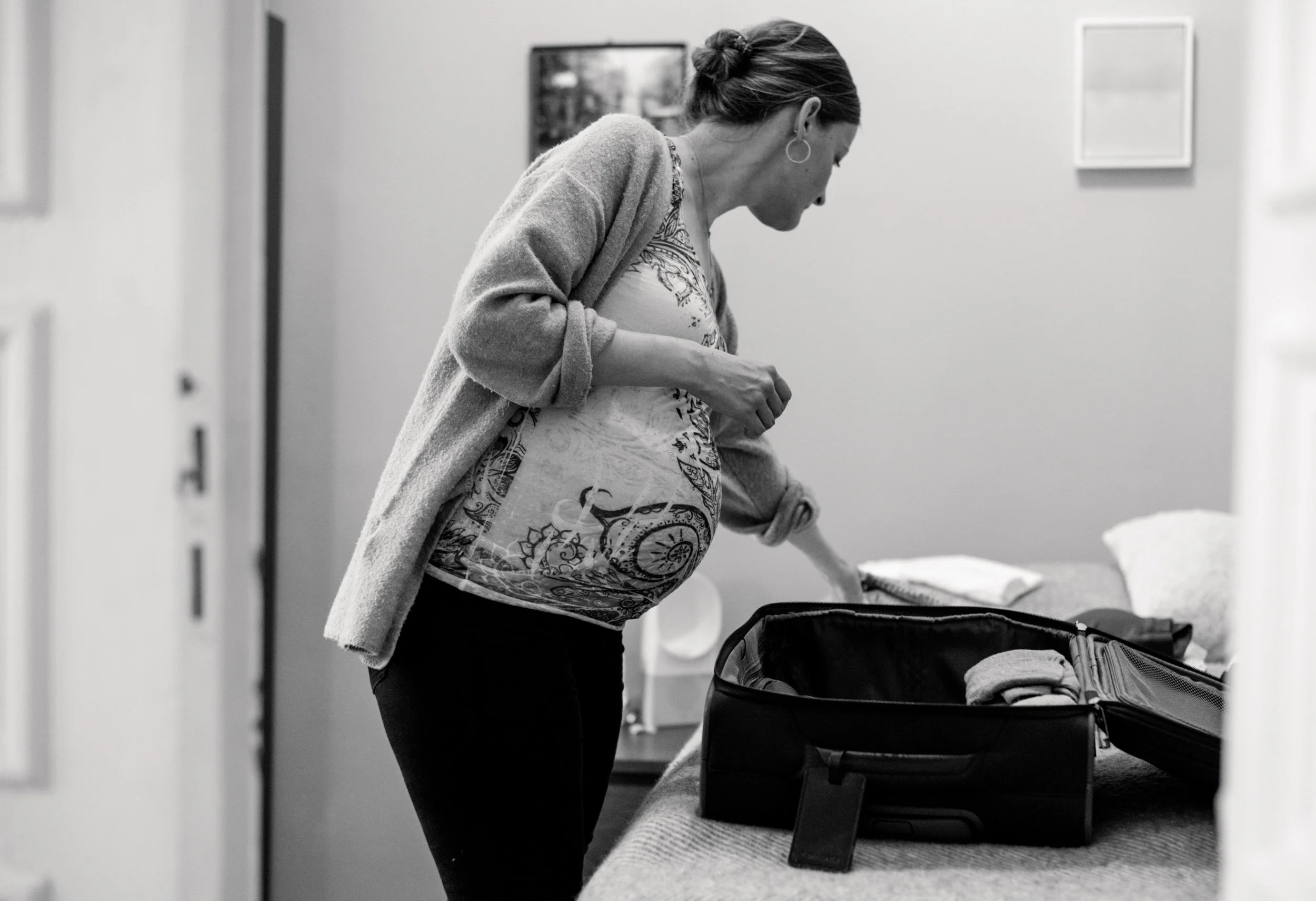 Schwangere Frau packt ihre Kliniktasche und fotografiert sich dabei selbst im 9. Schwangerschaftsmonat.