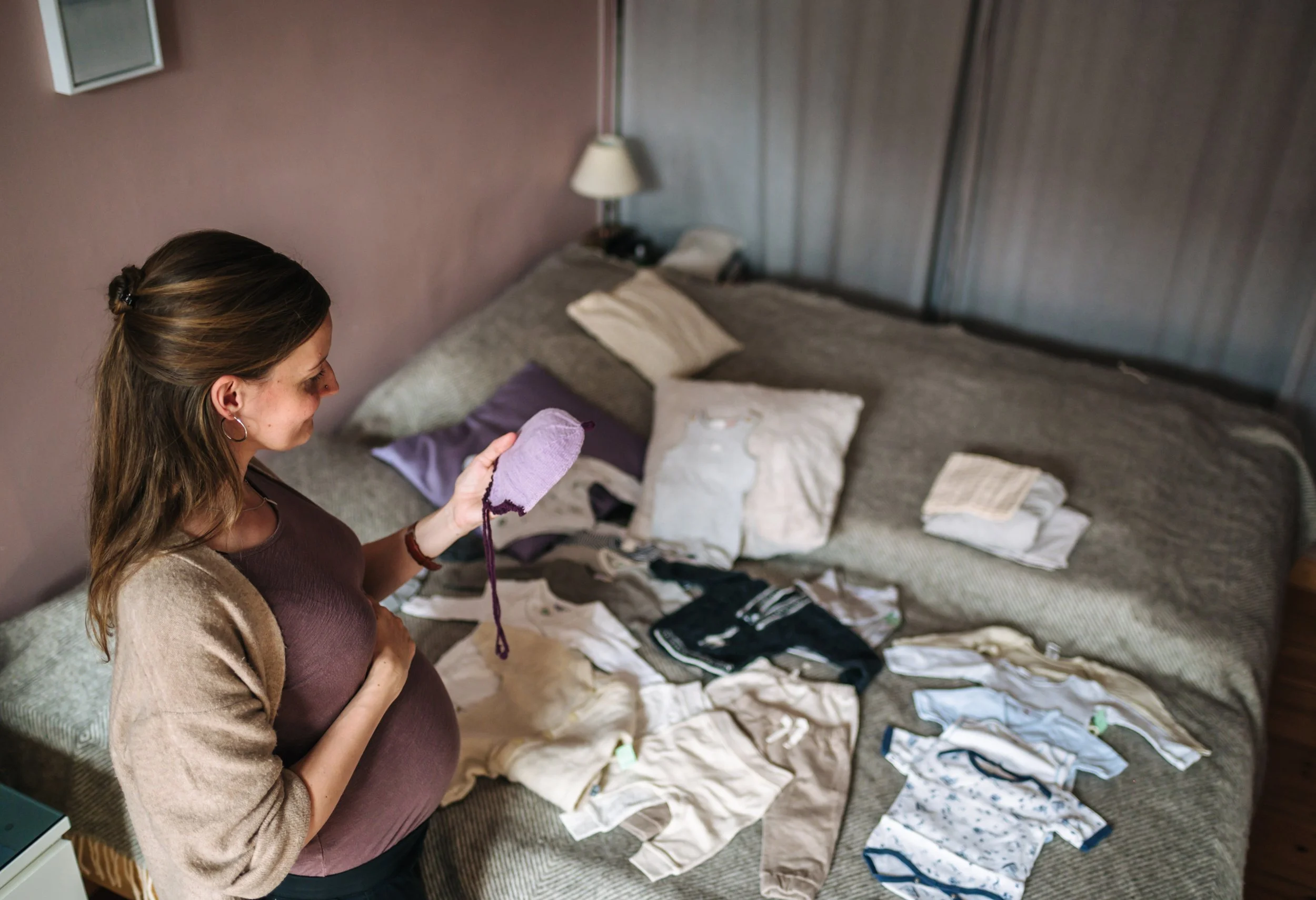 Selbstporträt einer schwangeren Frau mit den ersten Babysachen als Erinnerung an die Schwangerschaft.