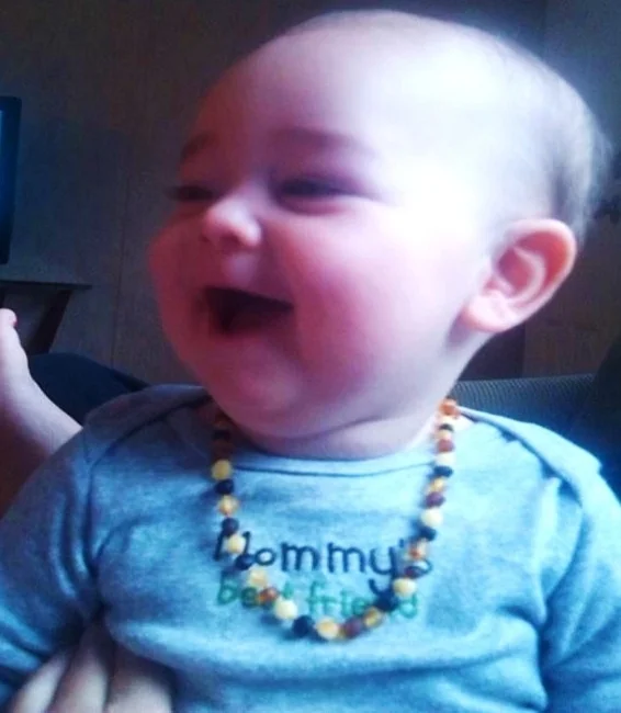 Happy teething baby while wearing a teething necklace from Staying Wild.