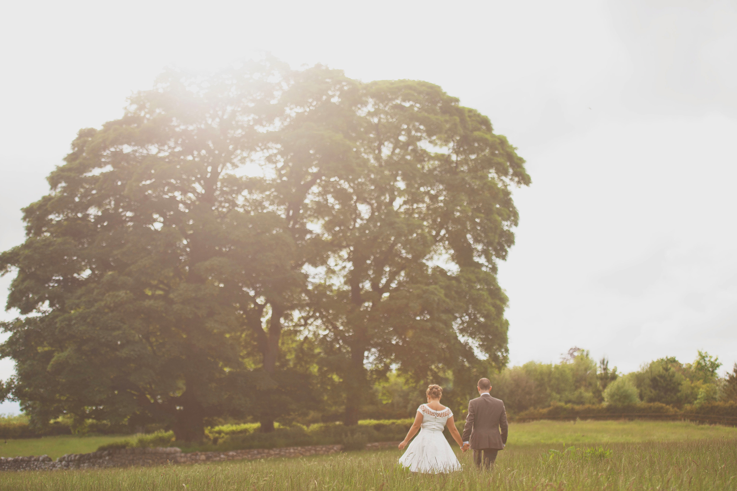 Couple walking through field in sunlight in Mount Druid, Westmeath