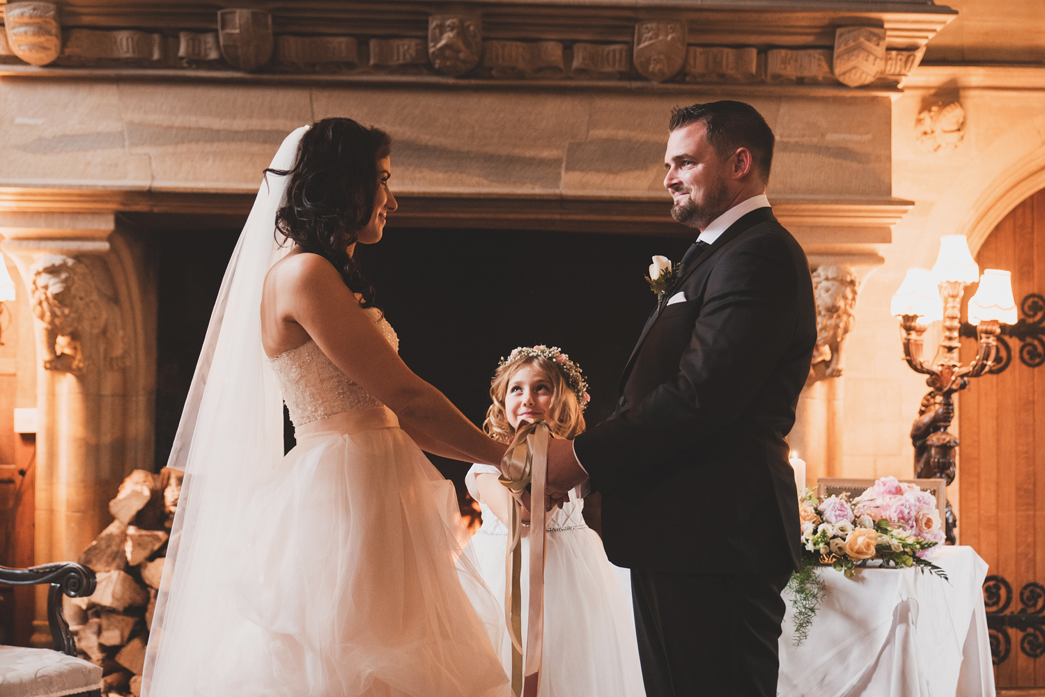 Bride and groom during ribbon tying ceremony with daughter. Waterford Castle, Ireland.