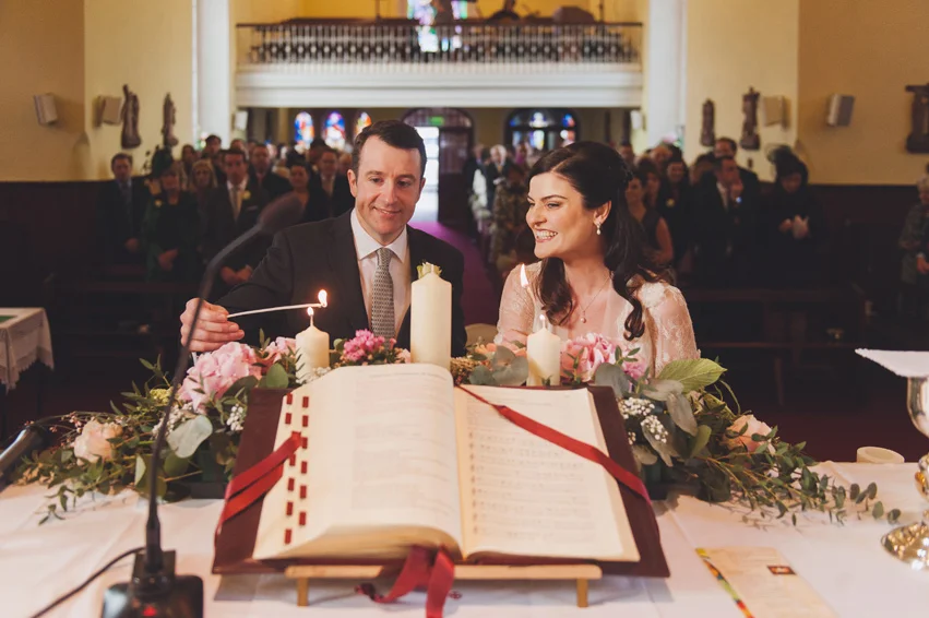 groom and bride lighting candles in the church 