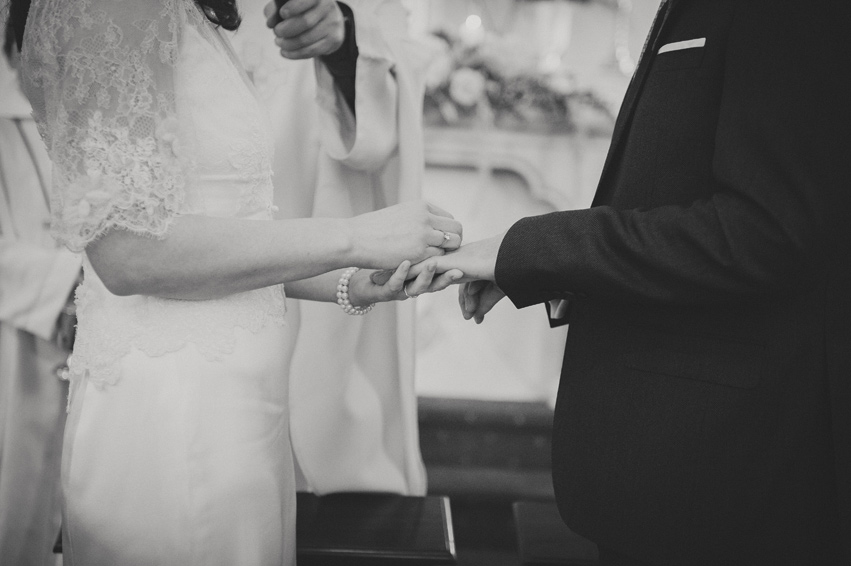 Bride putting ring on groom's finger in church