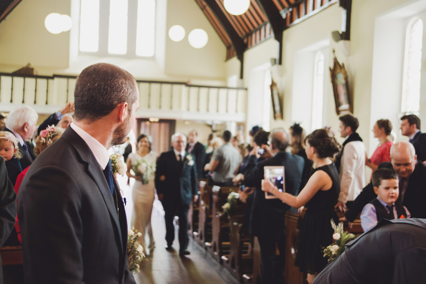 Groom looking at bride walking up the aisle in church. Wedding photography Meath.