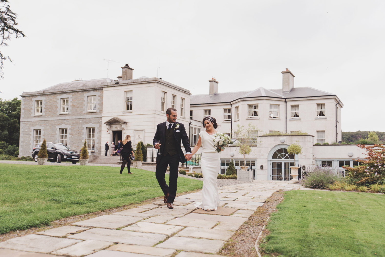 Bride and groom walking in front of Tankardstown House Meath Ireland. Wedding Photography