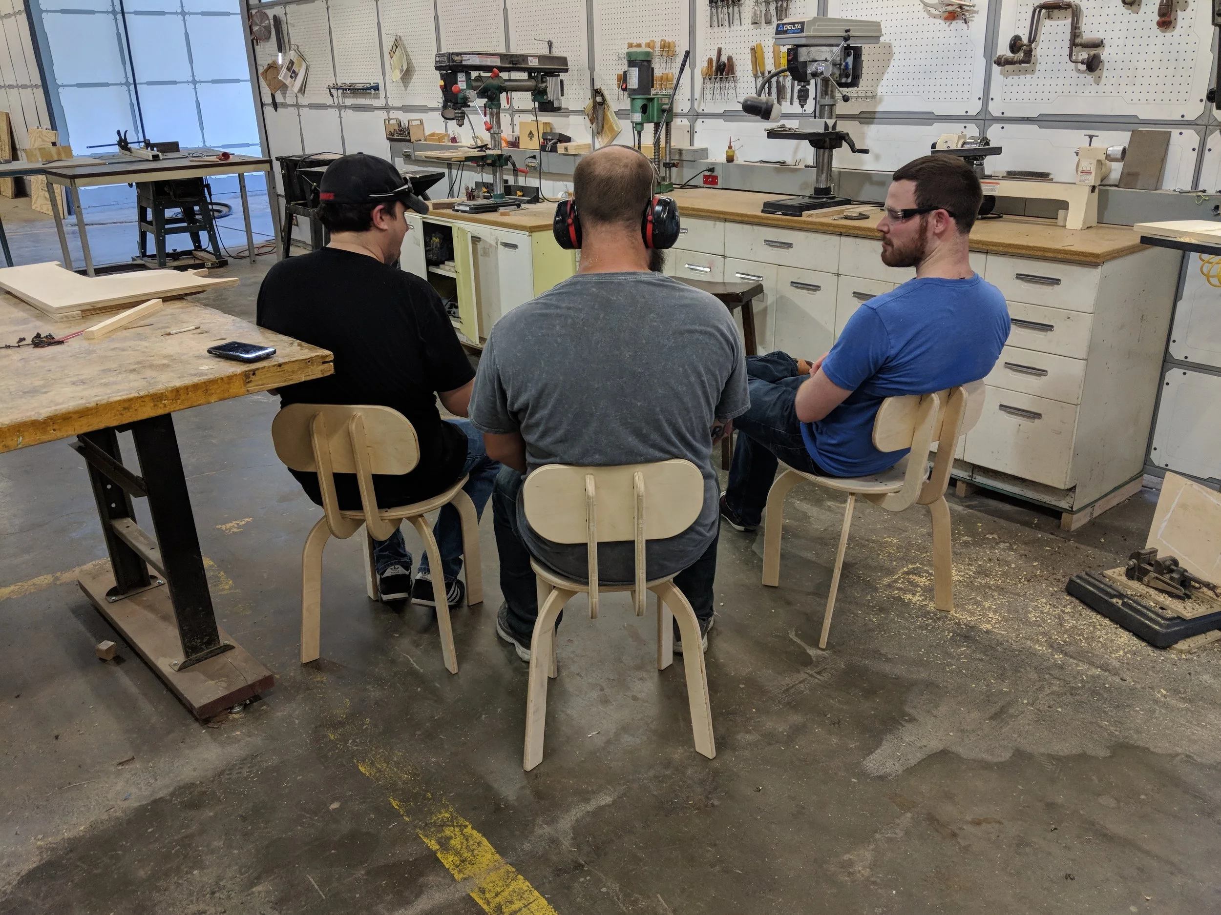 Three big men sitting on small Paramentric Chairs designed in Fusion 360