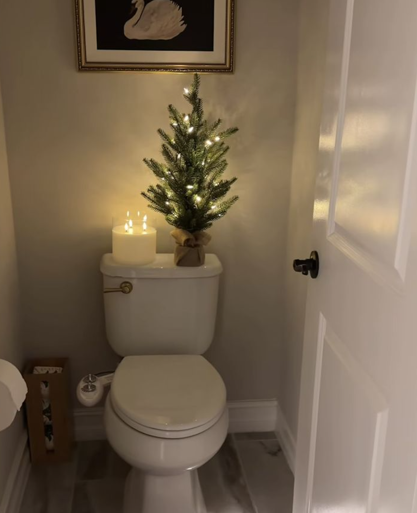 Tiny powder room decorated for Christmas with a small lit tree