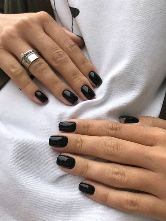 Short square black nails with a high-gloss finish, a classic Victoria Beckham-style manicure