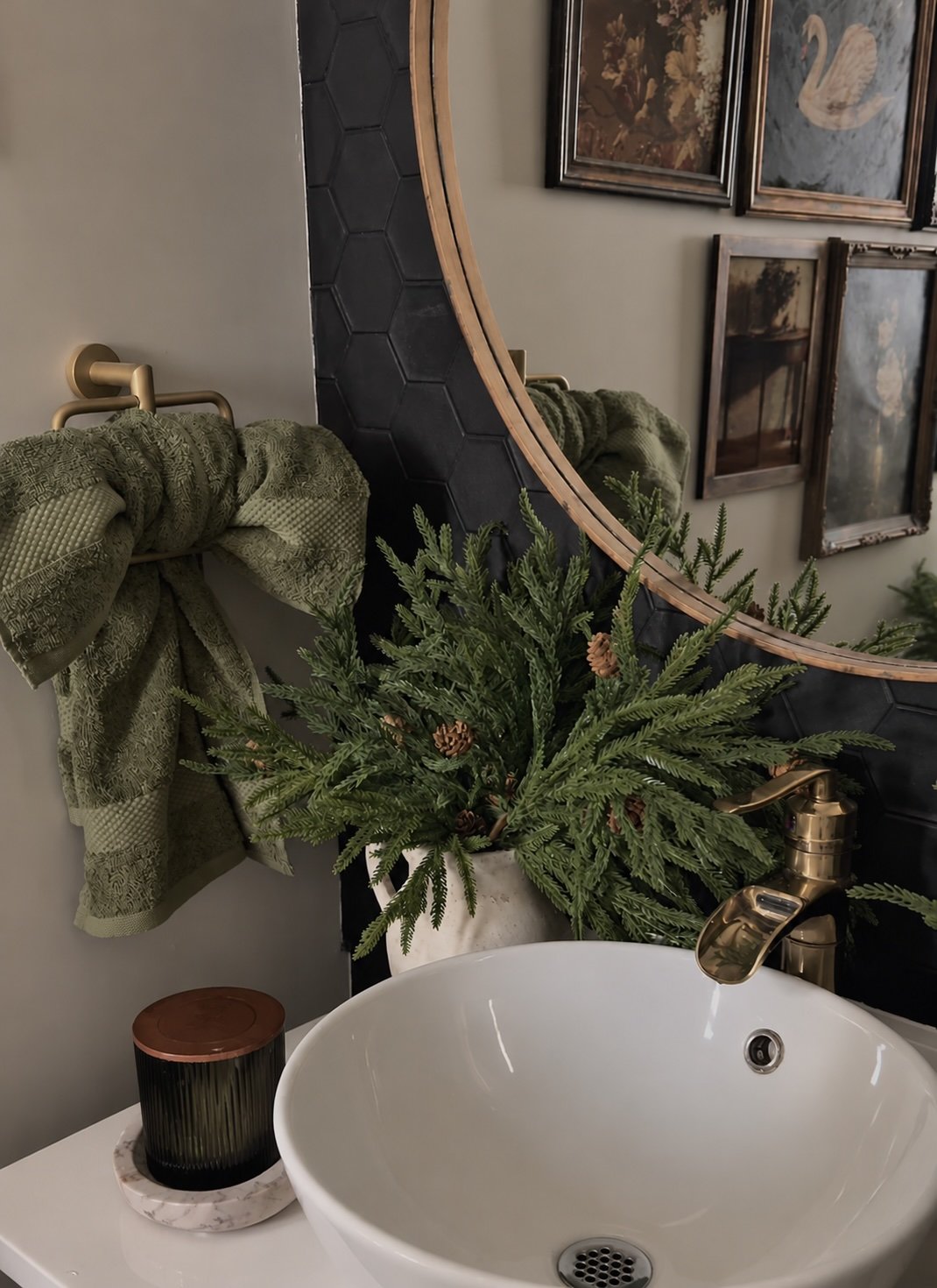 Moody Christmas bathroom with an olive green hand towel tied into a bow on a brass towel ring