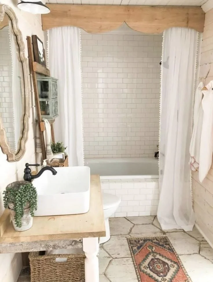 Light boho western bathroom with scalloped wood valance, pom-pom curtains, rustic wood vanity, and vintage rug
