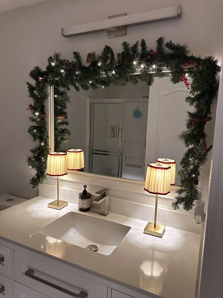 Apartment bathroom decorated for Christmas with lit pine garland, pinecones and red berries