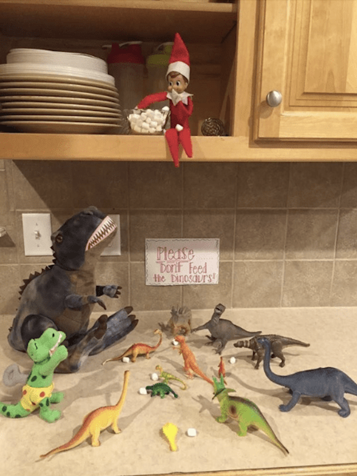 Elf on the Shelf feeding mini marshmallows to toy dinosaurs