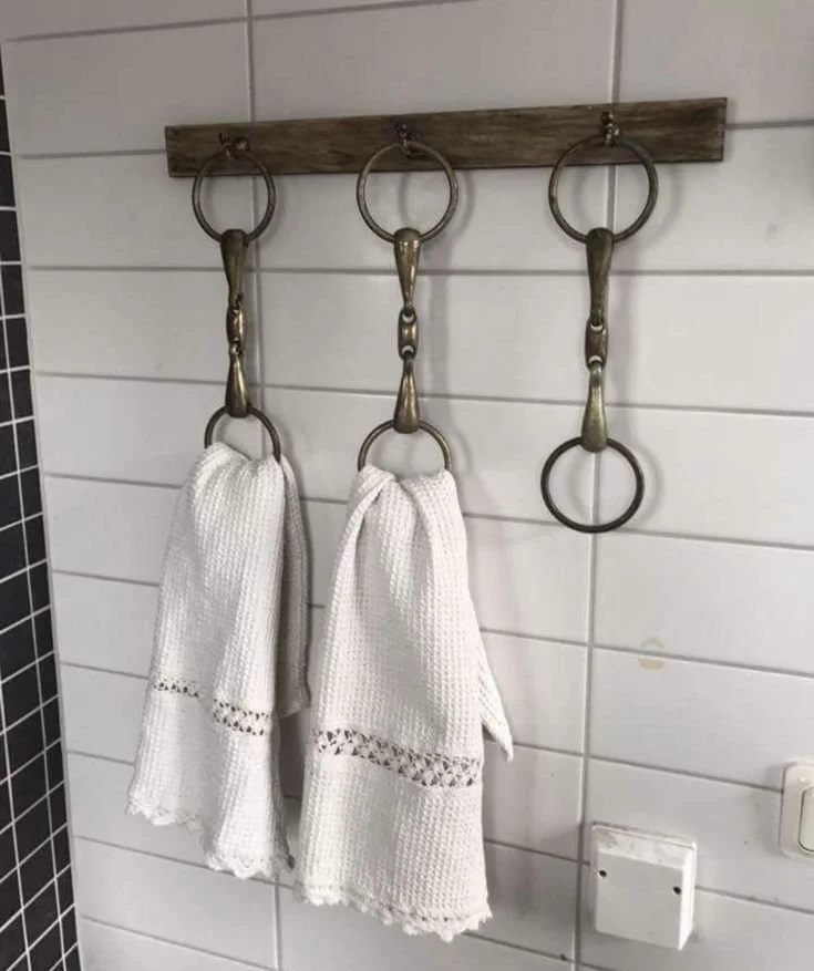 Equestrian bathroom towel rack made from vintage horse bits on reclaimed wood with white lace-trimmed towels