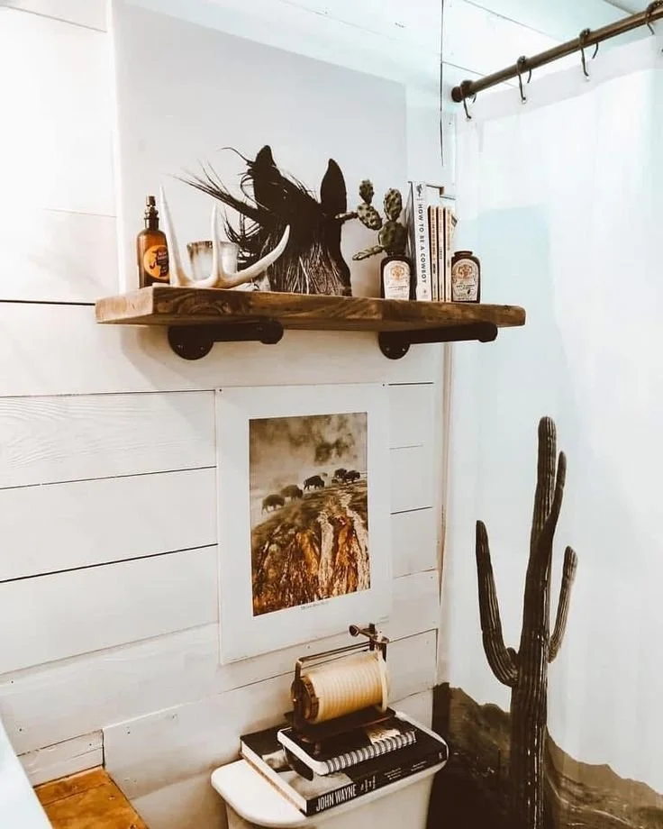 Desert cowboy bathroom with saguaro cactus shower curtain, reclaimed wood pipe shelf, antler decor, and bison print |
