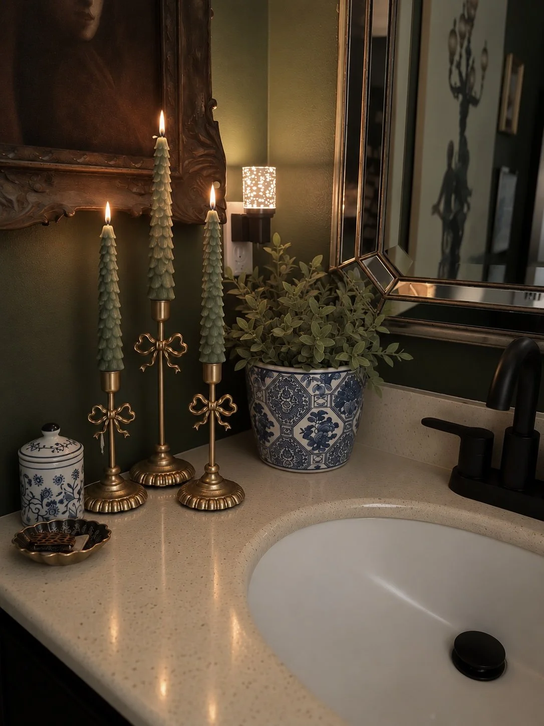 Christmas bathroom vanity with three sage green tree-shaped taper candles in brass bow candlestick holders,