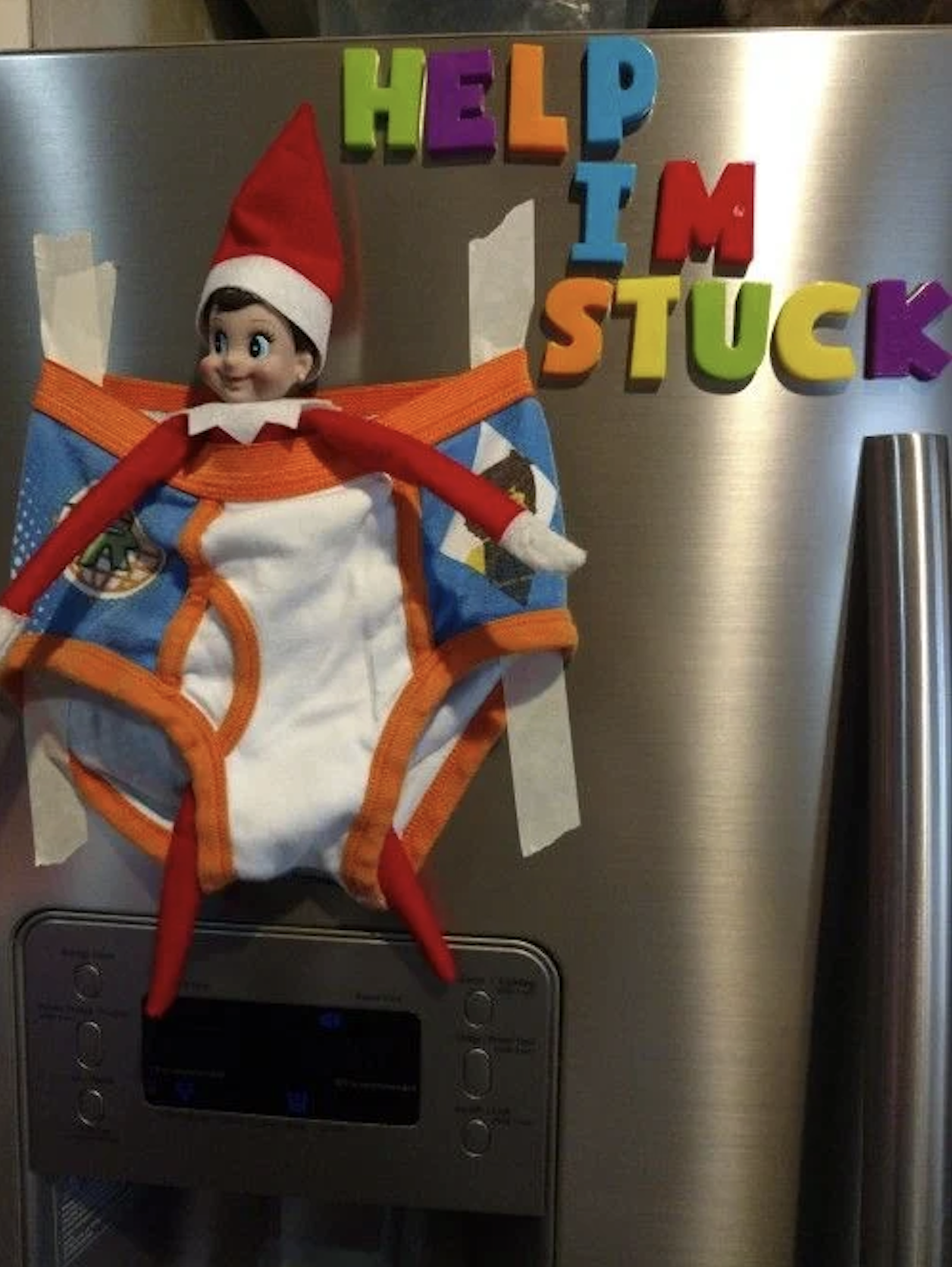 Elf on the Shelf taped to the fridge in underwear with a help me sign