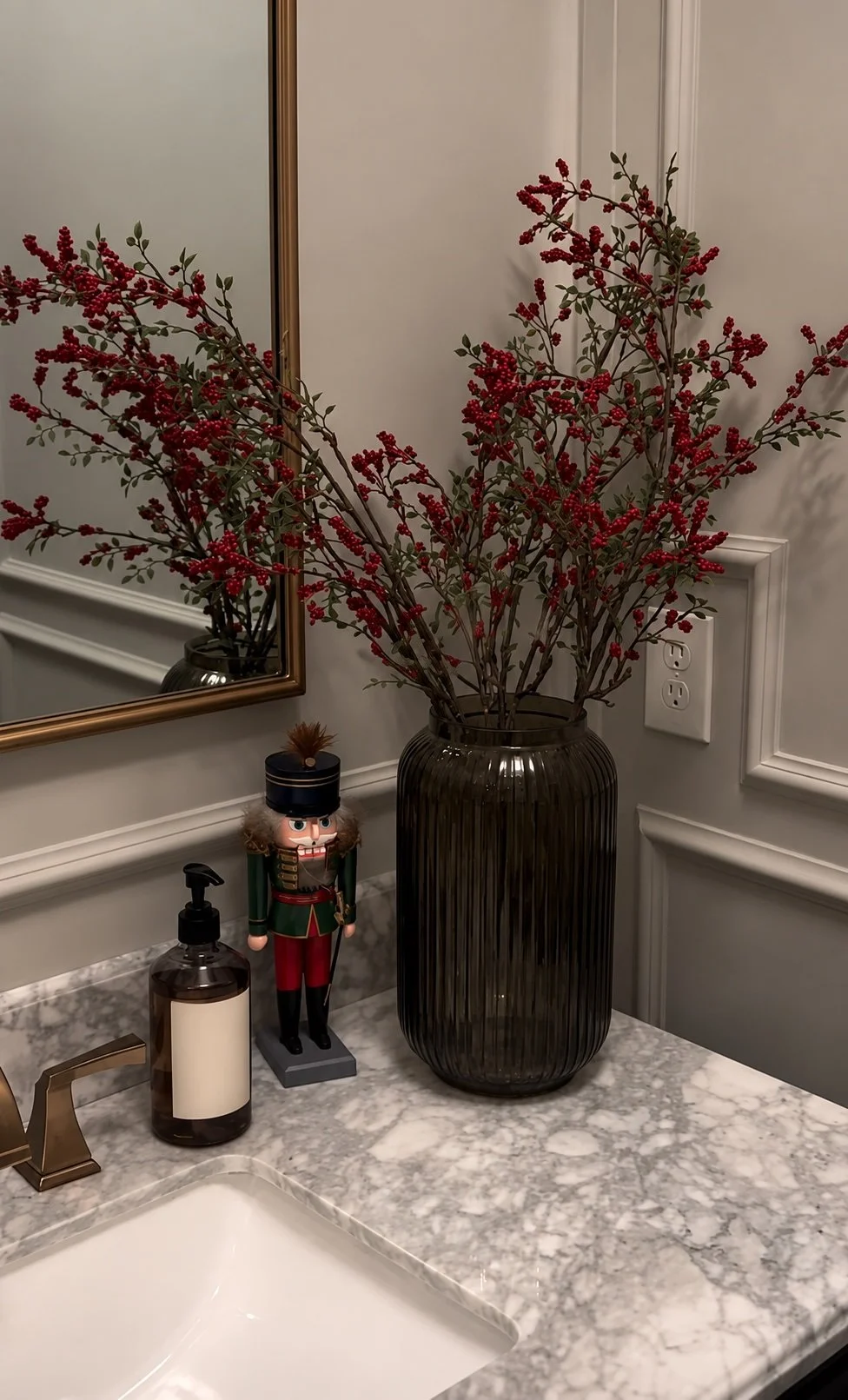 Christmas powder room vanity with tall red winterberry branches in a smoky ribbed glass vase