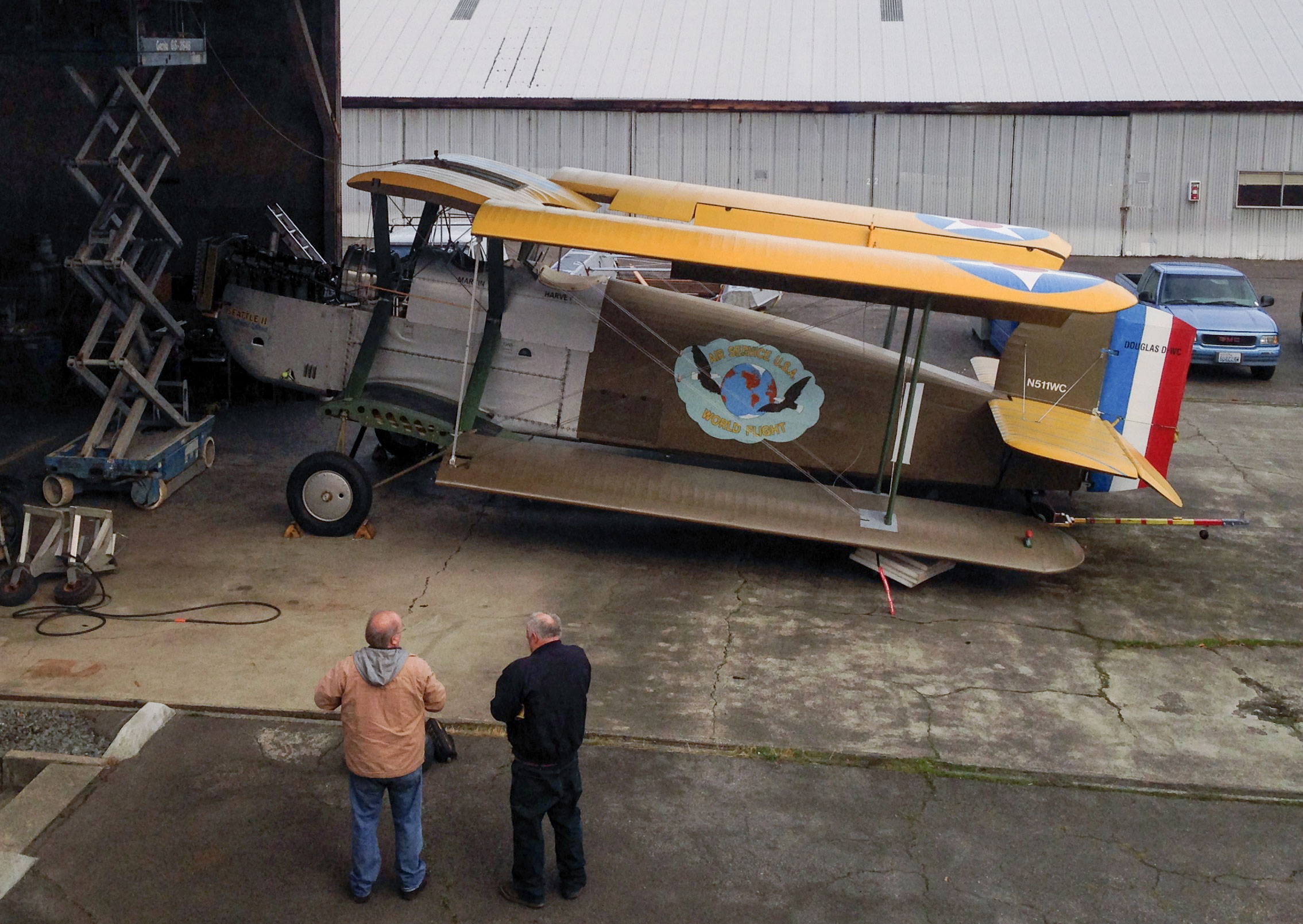 Bob on lift, checking hoist, Gary and Mitch in foreground. The wings are folded to get the plane in place under the hoist. 