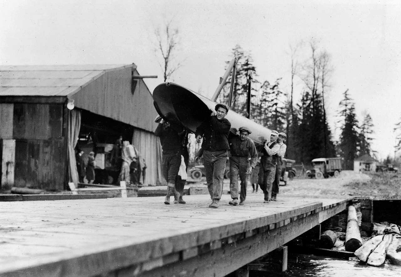 Boeing workers carrying the enormous pontoons across the dock. (Museum of Flight)