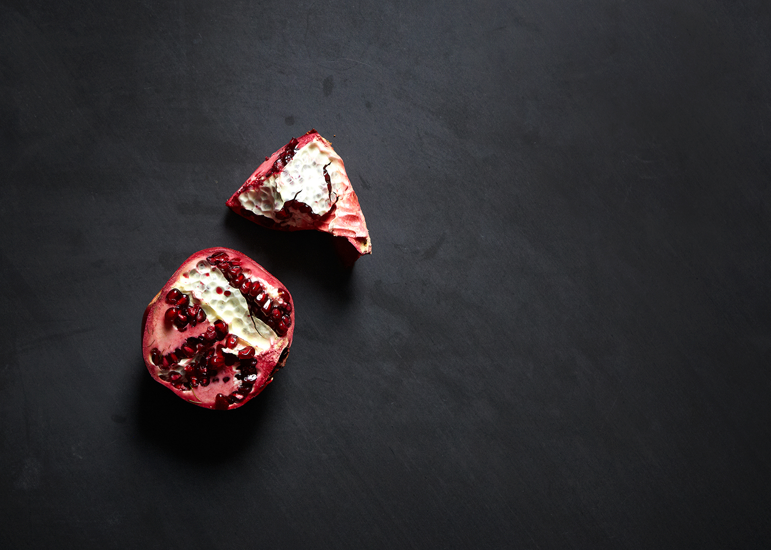 Pomegranate pieces on black slate.