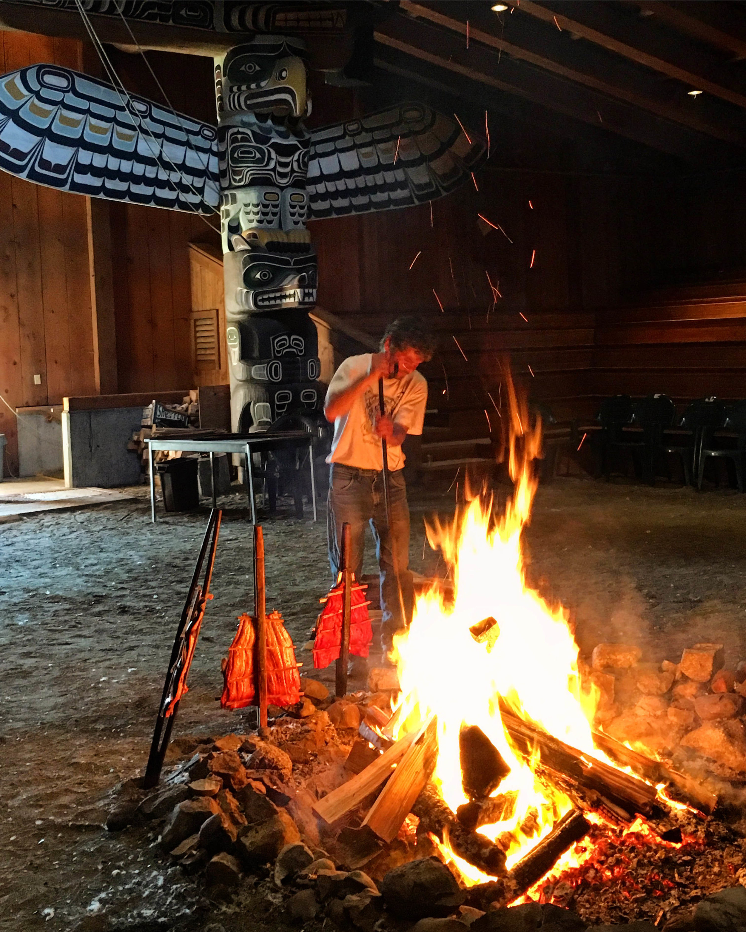 Billy stoking the fire and demonstrating barbecued salmon technique.